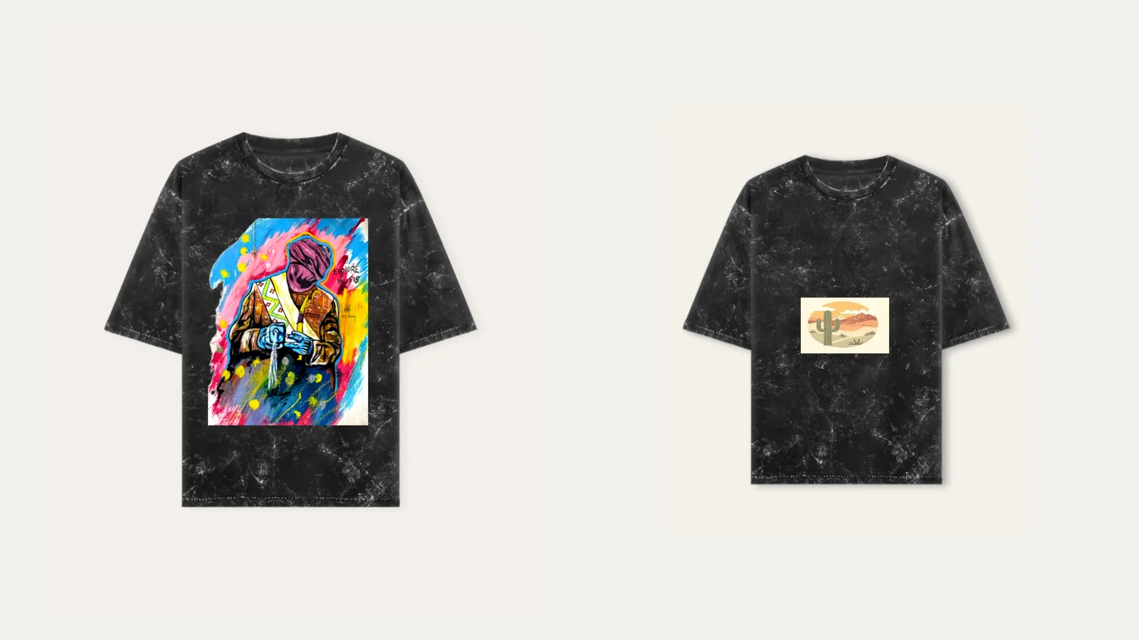 Two black acid wash oversized tees: one with a large colourful painted figure, one with a small desert cactus landscape print, both showing the grey marbled wash across the fabric.
